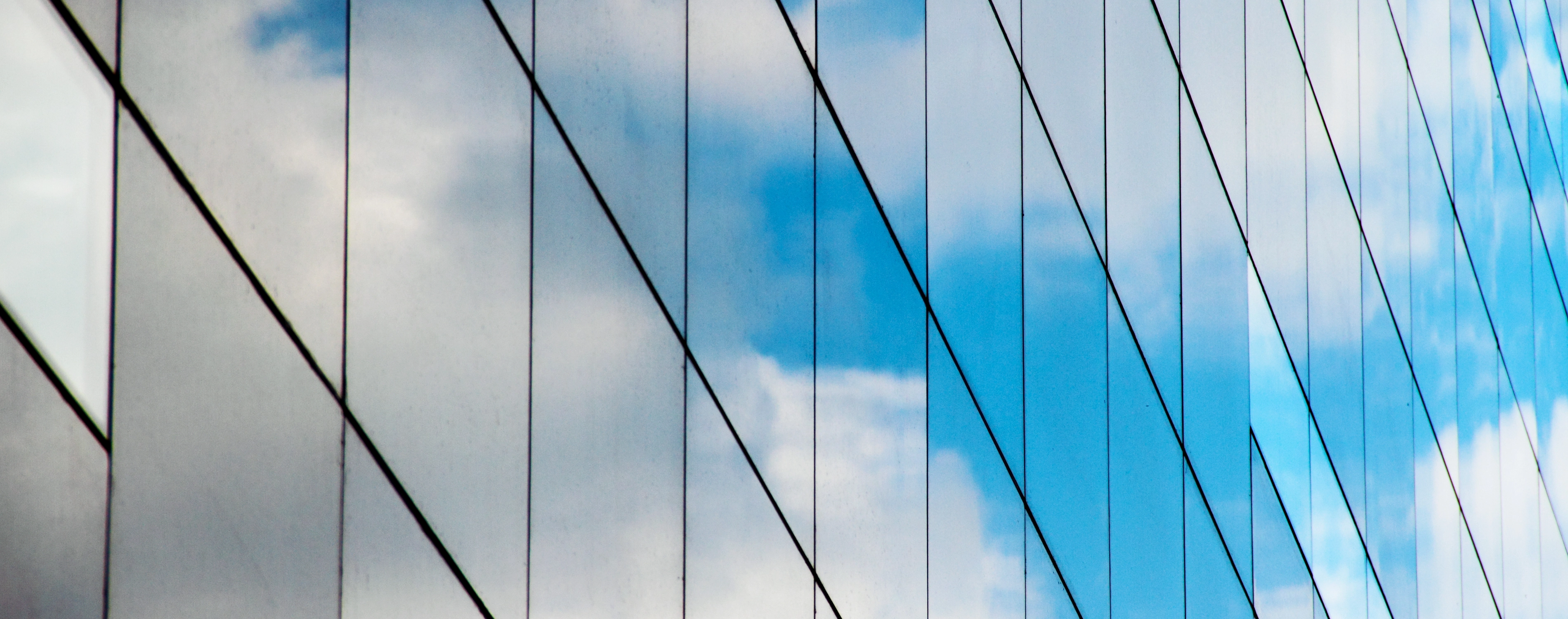 A reflection of clouds and sky in a mirrored glass building,